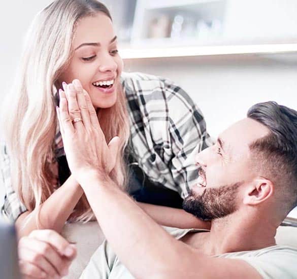 Young couple high fives while sitting on couch